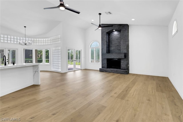 unfurnished living room with light wood-type flooring, french doors, and ceiling fan with notable chandelier