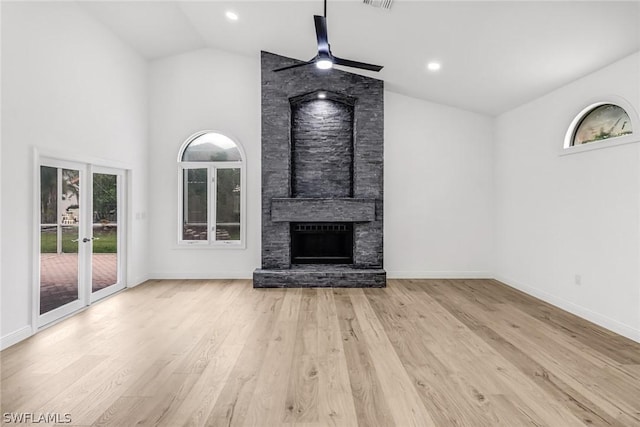 unfurnished living room with high vaulted ceiling, baseboards, wood finished floors, recessed lighting, and a stone fireplace