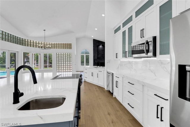 kitchen featuring a healthy amount of sunlight, a sink, appliances with stainless steel finishes, and lofted ceiling