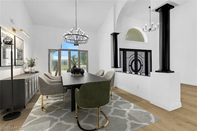 dining area with baseboards, high vaulted ceiling, wood finished floors, and a chandelier
