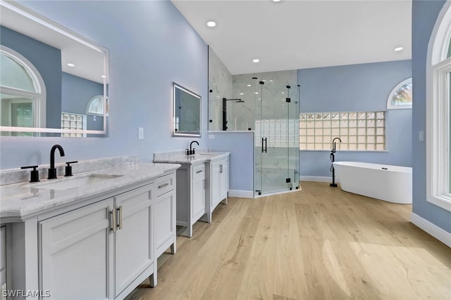full bath with a shower stall, wood finished floors, a sink, and two vanities