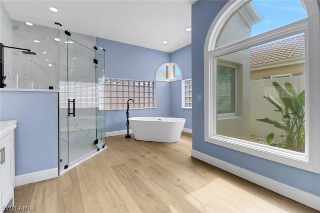 full bath featuring a marble finish shower, baseboards, wood finished floors, and a soaking tub