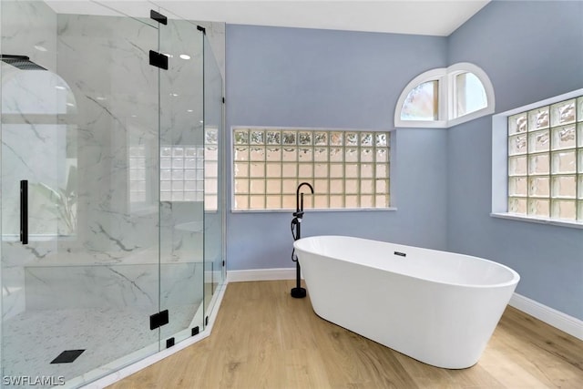 full bath with a marble finish shower, baseboards, wood finished floors, and a soaking tub