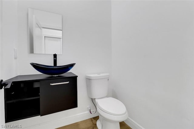 bathroom with baseboards, toilet, vanity, and wood finished floors