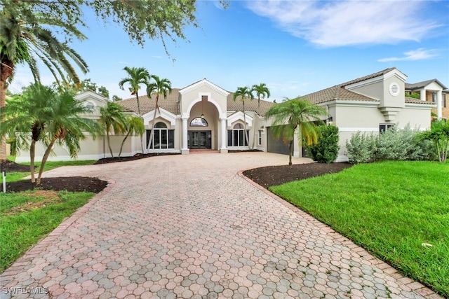 mediterranean / spanish home with a front lawn, decorative driveway, and stucco siding