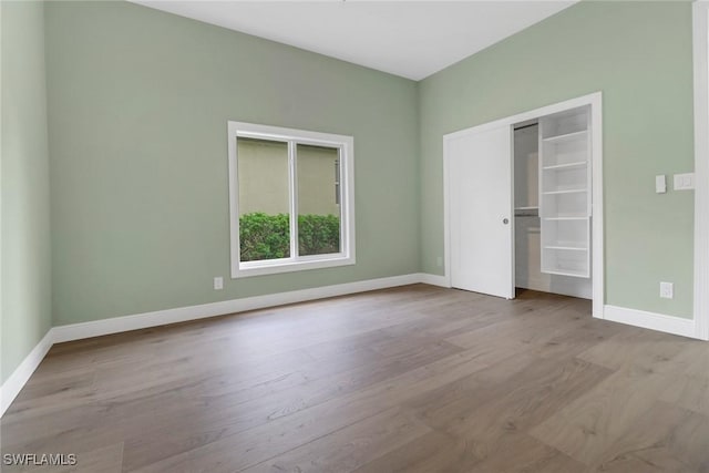 unfurnished bedroom with baseboards, wood finished floors, and a closet
