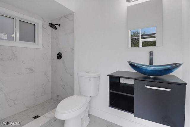 bathroom with vanity, a tile shower, toilet, baseboards, and marble finish floor