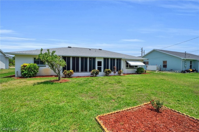 rear view of house featuring a sunroom and a lawn