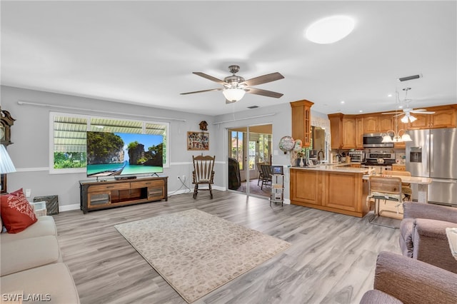 living room with a healthy amount of sunlight, sink, ceiling fan, and light wood-type flooring