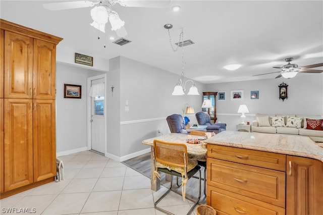 kitchen featuring light stone counters, decorative light fixtures, ceiling fan, and light tile floors