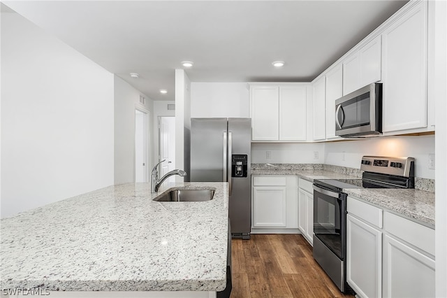 kitchen with dark hardwood / wood-style floors, stainless steel appliances, light stone counters, sink, and white cabinets