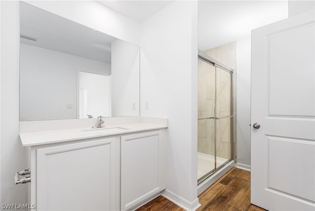 bathroom featuring a shower with shower door, wood-type flooring, and vanity with extensive cabinet space