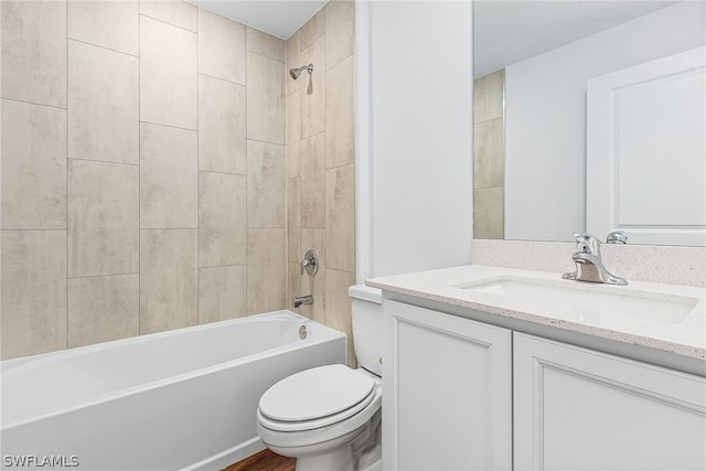 full bathroom featuring tiled shower / bath, vanity, and toilet