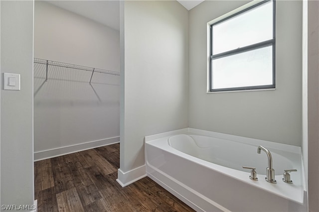 bathroom featuring plenty of natural light, hardwood / wood-style floors, and a bathing tub