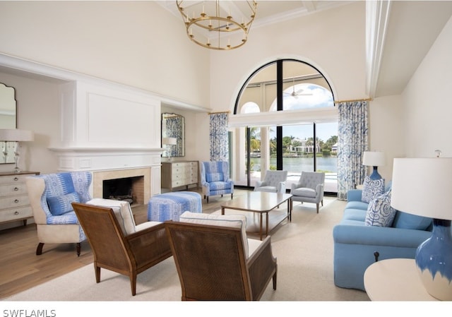 living room featuring a notable chandelier, a towering ceiling, a water view, and light hardwood / wood-style flooring