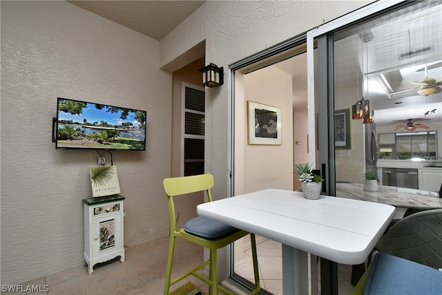 interior space with a kitchen breakfast bar, ceiling fan, and stainless steel dishwasher