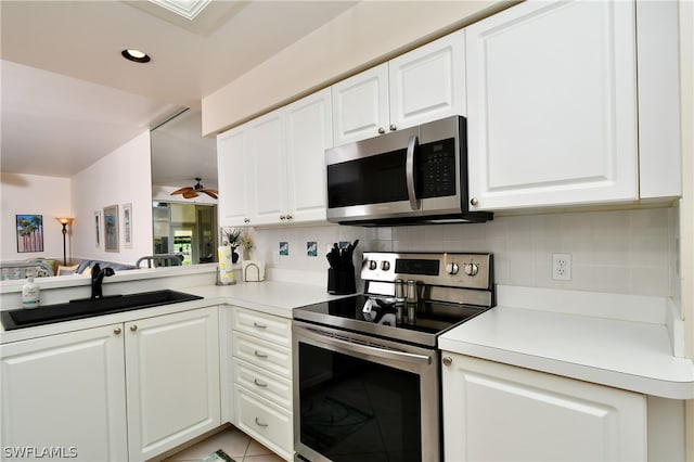 kitchen featuring backsplash, light tile floors, sink, white cabinetry, and appliances with stainless steel finishes