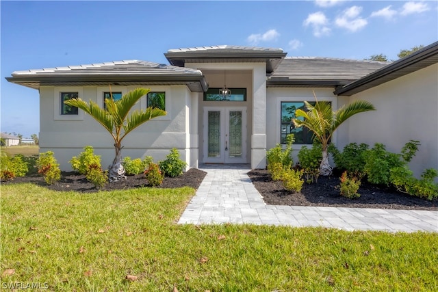 view of exterior entry with a yard and french doors