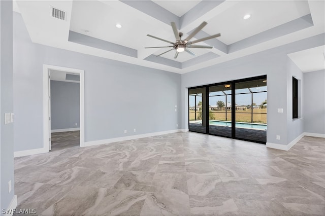 tiled spare room with a raised ceiling, coffered ceiling, and ceiling fan