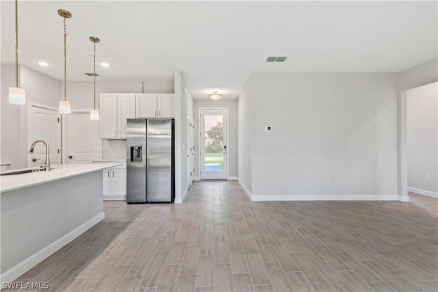 2206 NW 17th Pl, Cape Coral, FL 33993 - kitchen featuring white cabinetry, light wood-style flooring, stainless steel fridge, and a sink