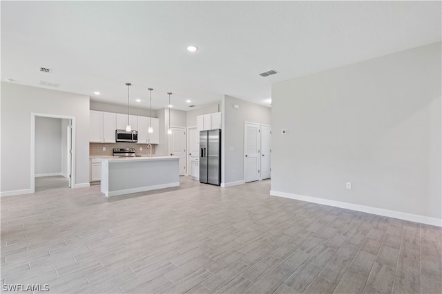 kitchen with white cabinets, hanging light fixtures, a kitchen island, and stainless steel appliances