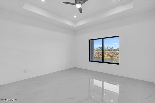 spare room featuring a raised ceiling and ceiling fan