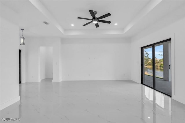 empty room featuring ceiling fan and a tray ceiling