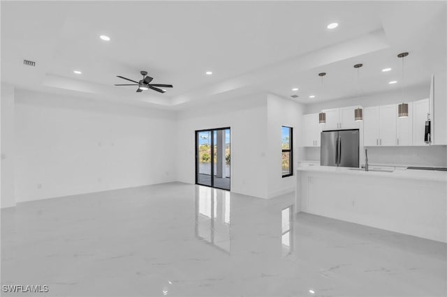 living room featuring ceiling fan, a raised ceiling, and sink