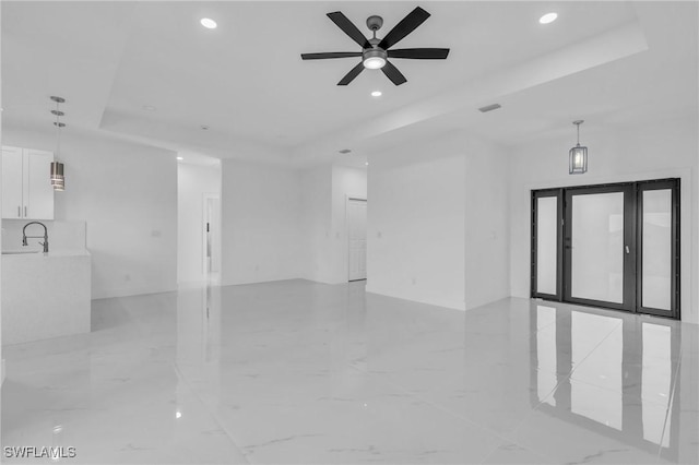 unfurnished room featuring a raised ceiling, ceiling fan, and sink