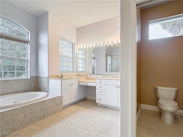 bathroom with tile patterned flooring, tiled bath, a healthy amount of sunlight, and vanity