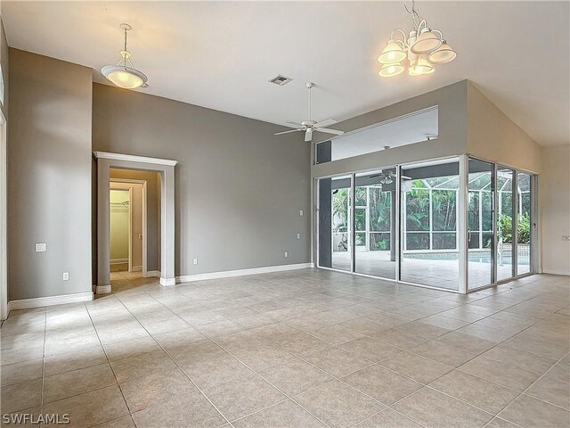 tiled empty room featuring ceiling fan with notable chandelier, a wealth of natural light, and high vaulted ceiling