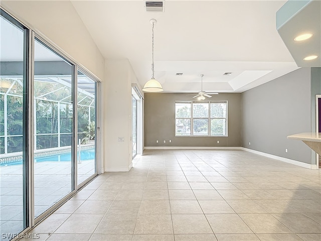 unfurnished room with ceiling fan, a tray ceiling, and light tile patterned floors