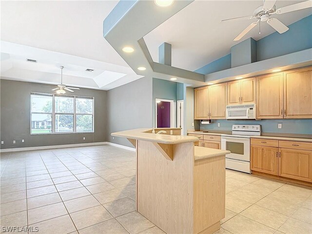 kitchen with a tray ceiling, ceiling fan, white appliances, and a breakfast bar