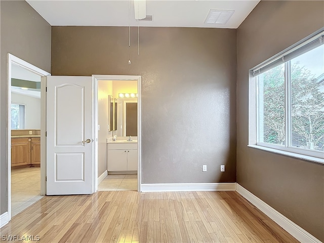 unfurnished bedroom featuring ensuite bath, ceiling fan, and light tile patterned floors