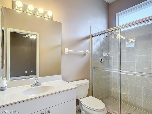 bathroom featuring a shower with door, vanity, ceiling fan, and toilet