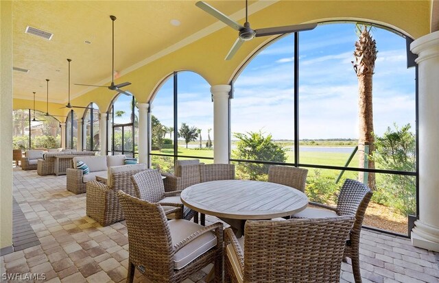 sunroom / solarium featuring a water view and ceiling fan