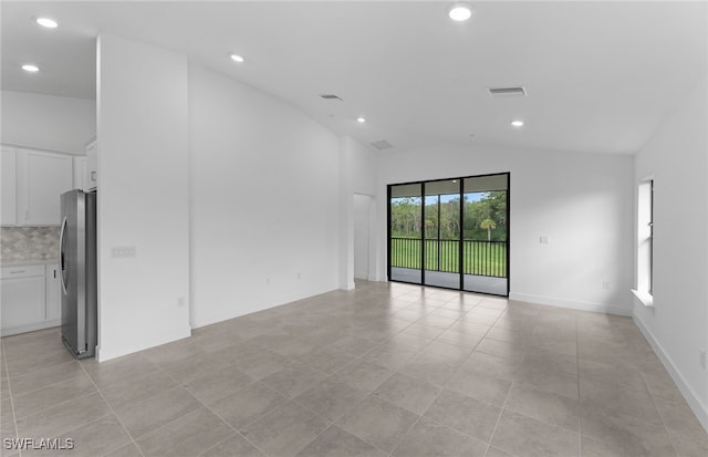 tiled spare room featuring vaulted ceiling