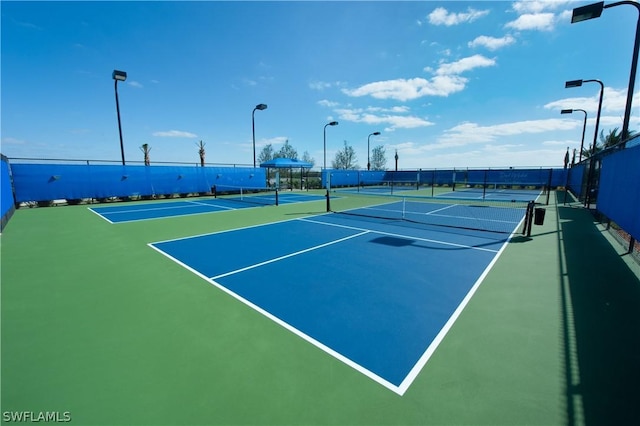 view of tennis court featuring community basketball court and fence