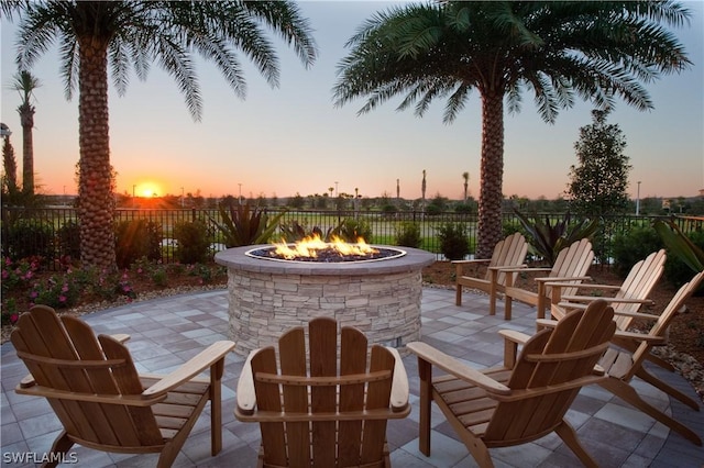 patio terrace at dusk featuring a fire pit and fence