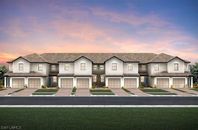 view of front of property with a front yard, driveway, a tiled roof, and stucco siding