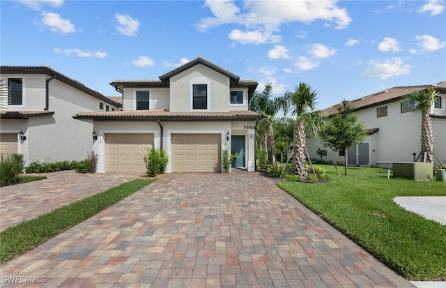 mediterranean / spanish house with a garage, a tiled roof, decorative driveway, stucco siding, and a front yard