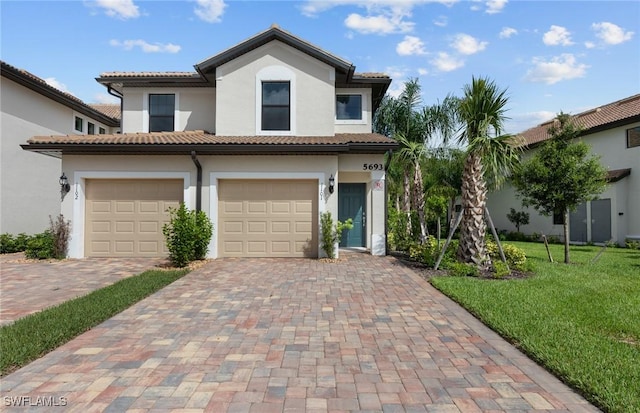 mediterranean / spanish house with a tile roof, an attached garage, decorative driveway, a front lawn, and stucco siding