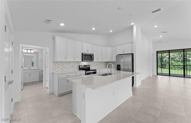 kitchen featuring stainless steel appliances, white cabinetry, sink, lofted ceiling, and an island with sink