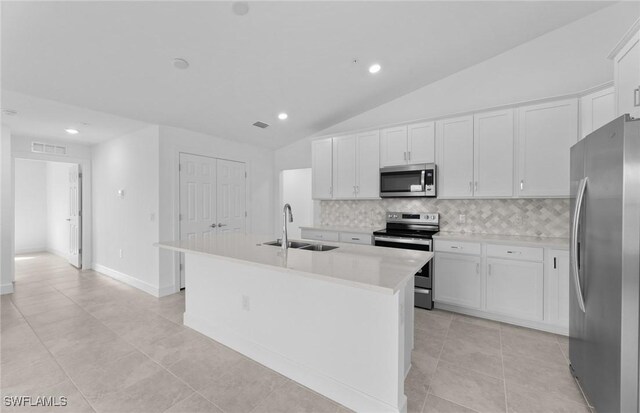 kitchen featuring appliances with stainless steel finishes, white cabinetry, a sink, and tasteful backsplash