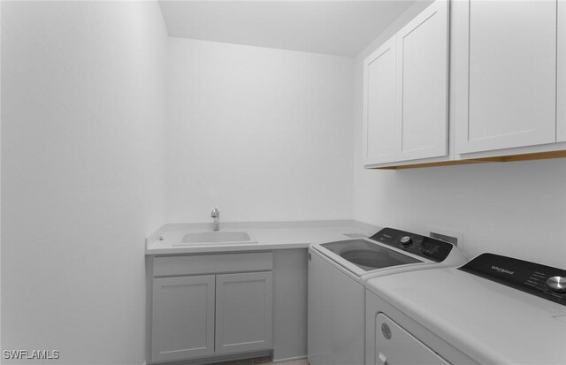 laundry room with cabinets, washer and clothes dryer, and sink