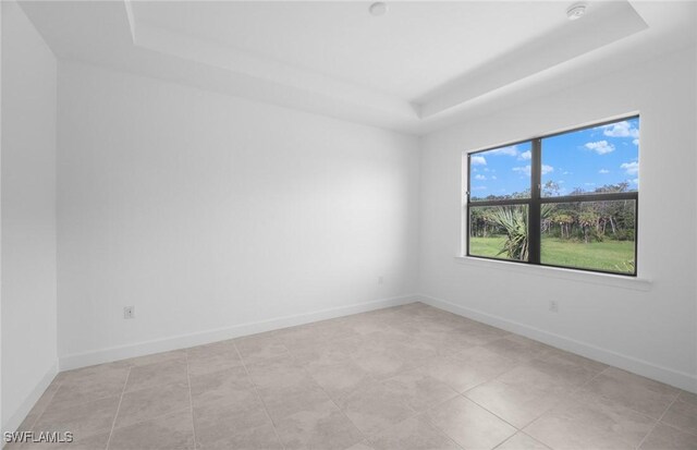 tiled spare room featuring a tray ceiling