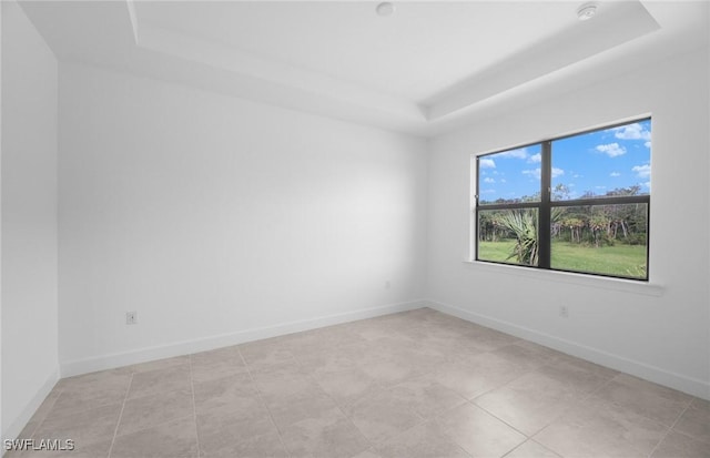 empty room with baseboards and a raised ceiling