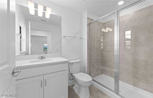 bathroom with vanity, toilet, an enclosed shower, and tile patterned floors