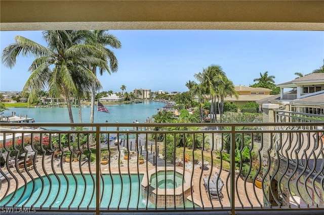 balcony with an in ground hot tub and a water view