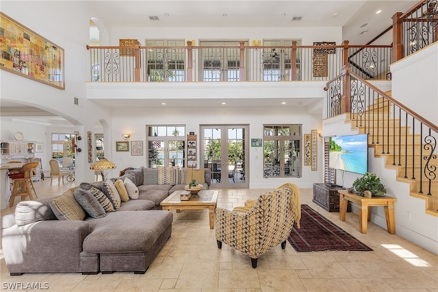 living room featuring a towering ceiling, light tile flooring, and french doors